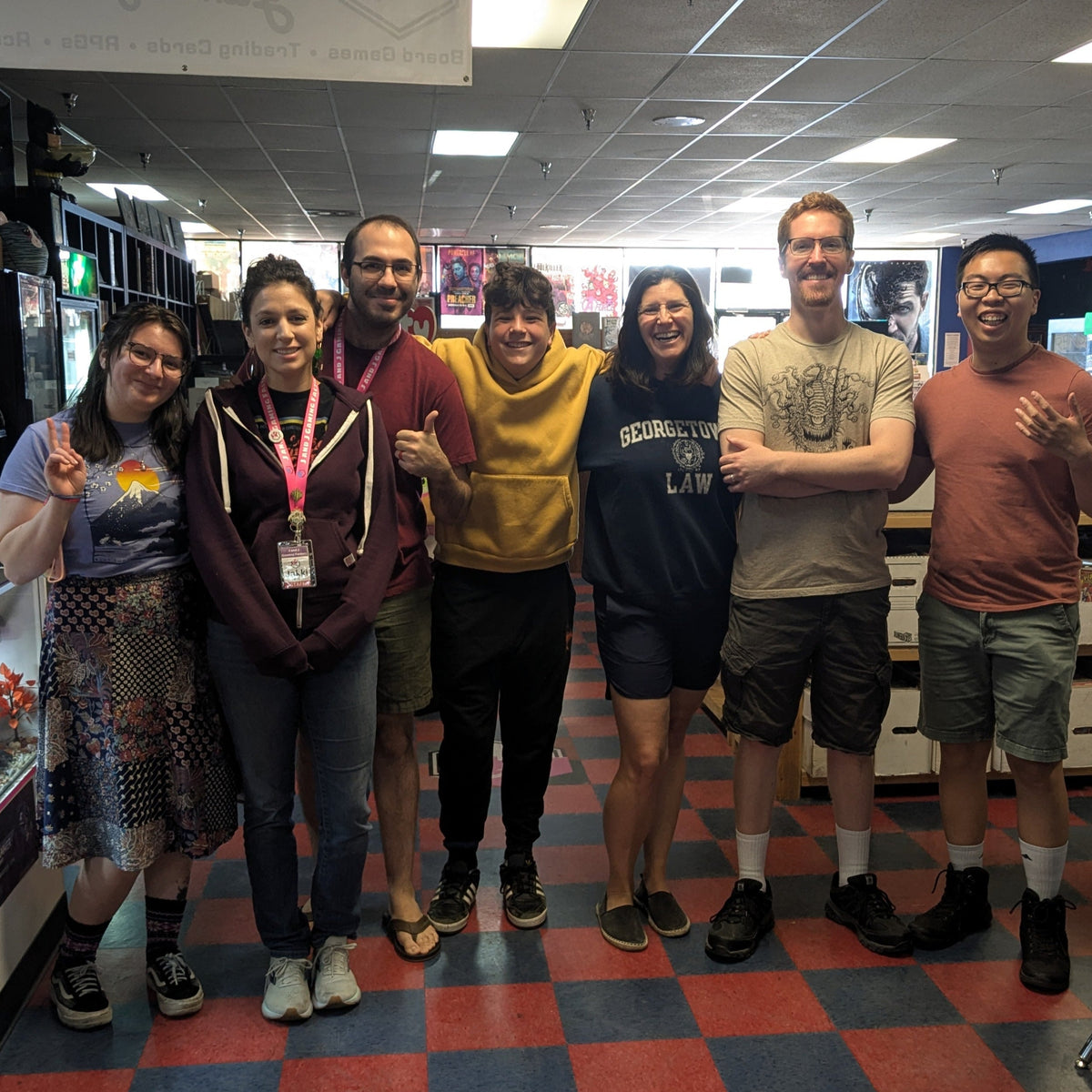Group of people posing for a photo in a store with a checkered floor.