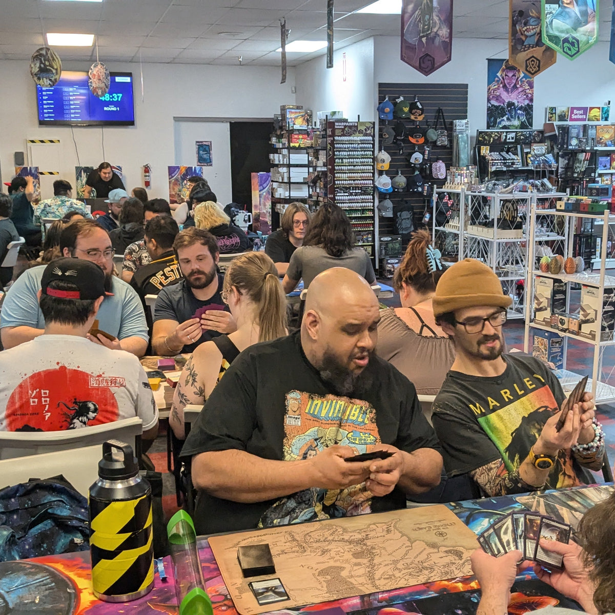People playing board games in a store with shelves of games and merchandise.